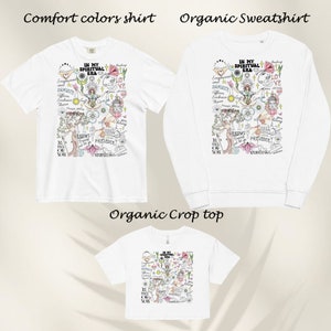 Puede incluir: Tres camisetas blancas con un estampado gr&aacute;fico colorido de un &aacute;rbol con el texto "In My Spiritual Era" en la parte delantera. Las camisetas est&aacute;n disponibles en manga corta, manga larga y estilo corto.