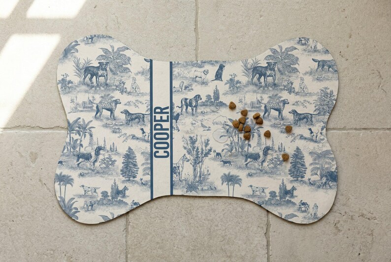 A bone-shaped dog food mat with a pattern of various animals and plants, placed on a tiled floor.