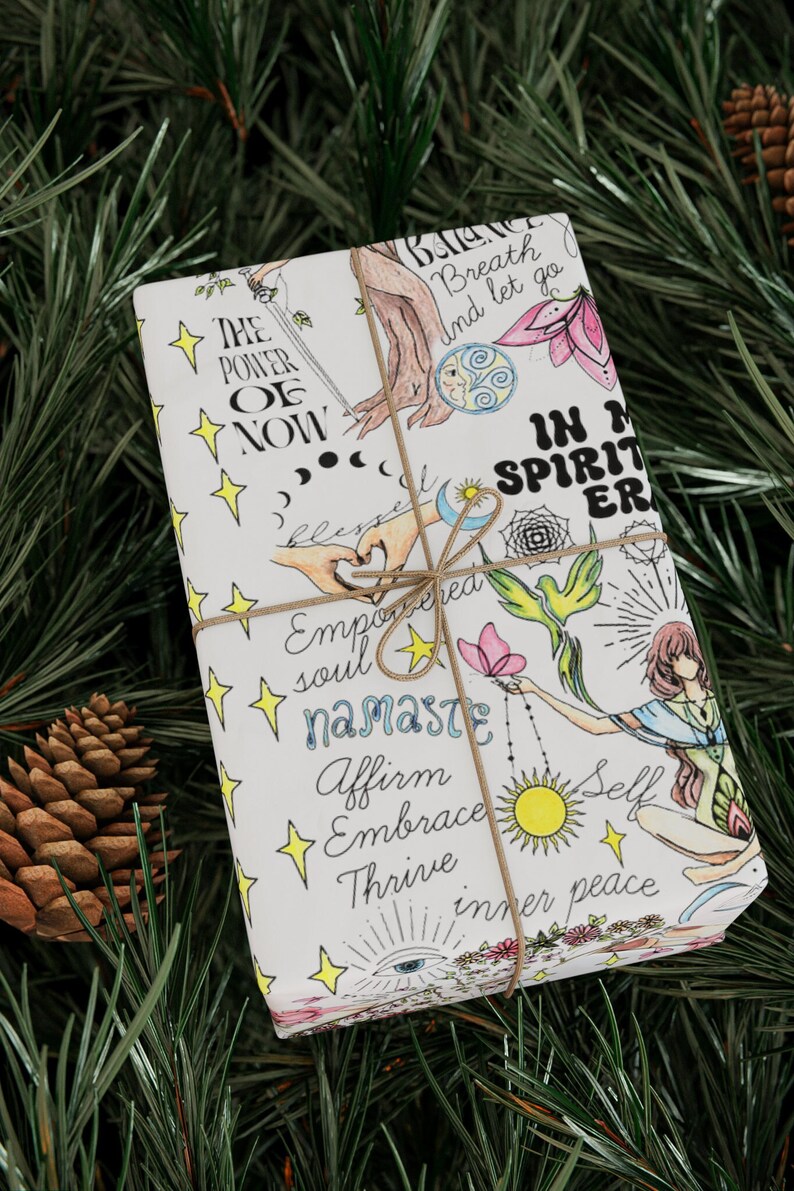 May include: White gift wrap with a colorful design featuring illustrations of hands, a butterfly, a bird, a sun, a moon, stars, and flowers. The text on the wrapping paper reads "The Power of Now", "Breath and let go", "In My Spirit", "Empowered Soul", "Namaste", "Affirm", "Embrace", "Thrive", "Self", and "Inner Peace".