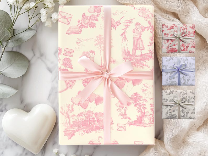 Pu&ograve; includere: Un regalo avvolto in carta a motivi rosa e bianchi con un nastro rosa. La carta presenta un motivo ripetitivo di cuori, palloncini e fiori. Tre scatole regalo pi&ugrave; piccole sono visibili sullo sfondo, avvolte in carta a motivi rosa, blu e grigi.