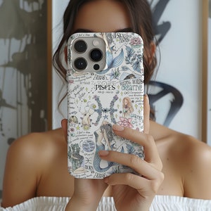 May include: A white phone case with a colorful design featuring a mermaid, stars, and the zodiac sign Pisces. The text on the case reads "Designed to Inspire", "Building Worlds", "Creative", "Compassion and kindness are my guiding stars", "I feel a deep connection with the world around me", "Born to Entrance", and "Cherishing souls embarking hearts".