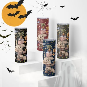 May include: Three stainless steel tumblers with a Halloween theme. The tumblers feature a black, navy blue, and burgundy background with a repeating pattern of a book, a witch's hat, a potion bottle, and a mandrake plant. The text "School of Craft" is printed on the book.