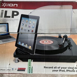 Könnte beinhalten: Ein schwarzes iLP Plattenspieler-Konvertierungssystem für iPad, iPhone und iPod. Die Box zeigt ein Bild des Plattenspielers mit einer Schallplatte, einem iPad und einem Laptop. Der Text auf der Box lautet: "Nehmen Sie Ihre gesamte Vinylmusik auf Ihr iPad, iPhone oder iPod auf:"