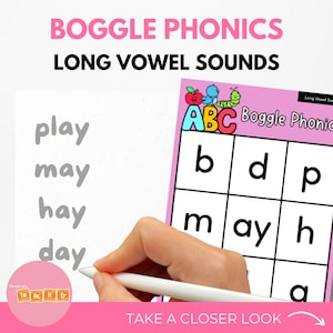 Pode incluir: Gráfico educativo rosa e branco com o texto "BOGGLE PHONICS LONG VOWEL SOUNDS". A imagem inclui as palavras "play, may, hay, day" e uma grelha de letras. Uma mão segura uma caneta branca, apontando para as palavras.