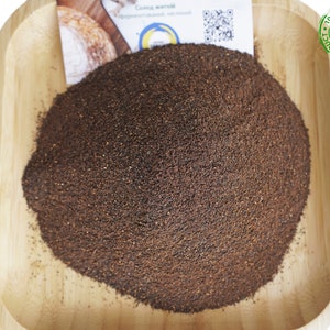 May include: A close-up of a brown powder in a wooden bowl. The powder is labelled as 100% organic and natural product.