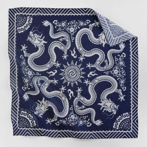 May include: A blue bandana with a white pattern of four dragons and a sun in the center. The bandana has a white border with a repeating pattern of white triangles.