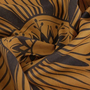 May include: A brown fabric with a black geometric pattern. The pattern features a repeating design of lines and circles.