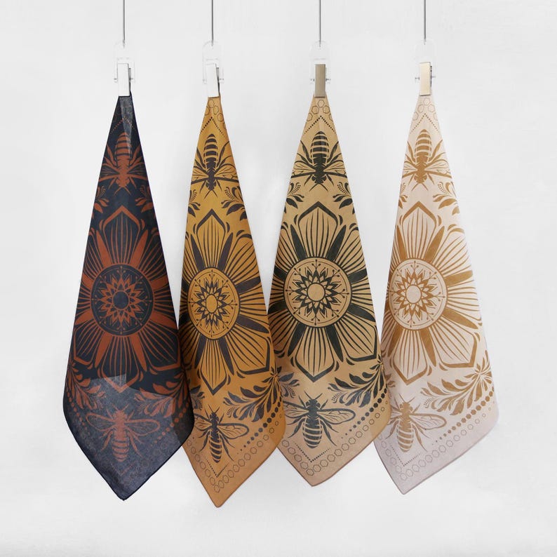 May include: Three fabric tea towels with a bee and flower mandala design. The towels are in shades of brown, tan, and beige.