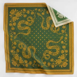 Puede incluir: Un pañuelo verde con borde dorado y un patrón repetido de serpientes, rosas y hojas. El pañuelo está hecho de 100% algodón y tiene el texto "USA Textile" impreso en él.