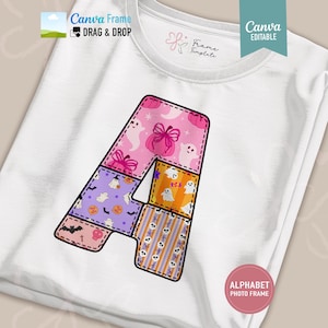 May include: A white t-shirt featuring a large letter A graphic. The letter is divided into sections with various Halloween-themed patterns including ghosts, pumpkins, bats, and skulls in shades of pink, purple, orange, and white. The design includes text.