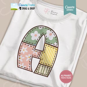 Puede incluir: Una camiseta blanca con un gráfico grande de la letra A diseñado como un marco de patchwork. La letra se compone de segmentos con patrones florales verdes, florales rosas, rayas amarillas y rayas verdes, delineados con un efecto de costura.