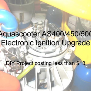 May include: Close-up of a small engine with a yellow handle and blue and yellow hoses. The text "Aquascooter AS400/450/500 Electronic Ignition Upgrade DIY Project costing less than £13" is visible on the image.