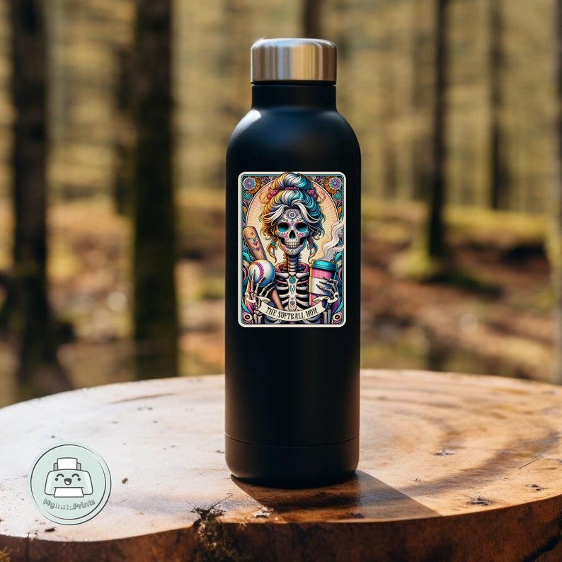 May include: Black stainless steel water bottle with a colorful sticker featuring a skeleton woman holding a baseball bat and a coffee cup. The sticker says "The Softball Mom".