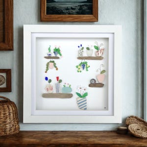 Sea glass and driftwood framed art, hanging baskets, flower pots and vases on shelves, coastal home wall decor