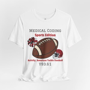 May include: A white t-shirt featuring the text MEDICAL CODING Sports Edition, a brown American football, a red and white pom-pom, a red football helmet, and the text Activity, American Tackle Football Y93.61 printed on the front centre.