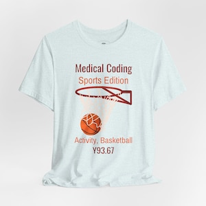 Op de afbeelding: Een lichtblauw t-shirt met een afbeelding van een basketbalring en een bal. De tekst luidt Medical Coding Sports Edition, Activity, Basketball en Y93.67. Het ontwerp gebruikt donkerrode en oranje kleuren en is gecentreerd op het kledingstuk.