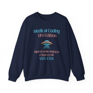 Puede incluir: Sudadera azul marino con un gráfico de un OVNI y el texto "Medical Coding UFO Edition" y "Injured while Riding in a Spacecraft V95.43XA".