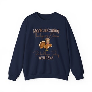 May include: Navy blue sweatshirt with a brown turkey wearing a paper bag on its head. The text "Medical Coding Thanksgiving Edition" and "Pecked by a Turkey W61.43XA" is printed on the sweatshirt.