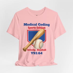 May include: A light pink t-shirt featuring a graphic of a wooden baseball bat and a white baseball over a blue home plate emblem. The text reads Medical Coding Sports Edition Activity, Baseball Y93.64 in blue and red lettering on the front.