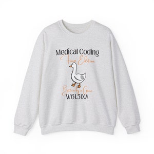 May include: Light gray sweatshirt with the text "Medical Coding Farm Edition" and a cartoon goose illustration. Below the goose is the text "Bitten by a Goose W61.51XA". The sweatshirt is a crew neck style.