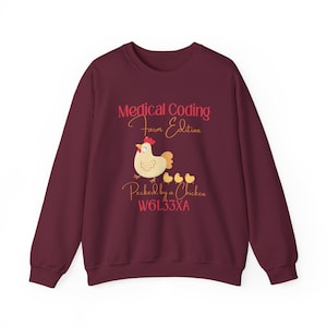 Op de afbeelding: Bordeaux sweatshirt met de tekst "Medical Coding Farm Edition" en een afbeelding van een kip en kuikens. De zin "Pecked by a Chicken" staat eronder, samen met de code W61.33XA.