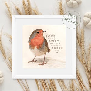 May include: A white framed print featuring a robin perched on a light brown surface. The print includes the text "Those we love don't go away they walk beside us every day".