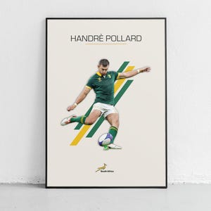 May include: A framed poster featuring rugby player Handrè Pollard in action, kicking a ball. He wears a green and gold jersey and white shorts. The poster has a cream background with green and yellow diagonal stripes and the South Africa logo.