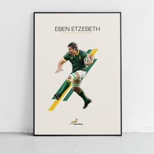 Puede incluir: Un póster enmarcado con Eben Etzebeth con uniforme de rugby verde y dorado, sosteniendo un balón de rugby. El póster tiene un fondo crema con un diseño geométrico amarillo y verde. El texto "EBEN ETZEBETH" está en la parte superior.