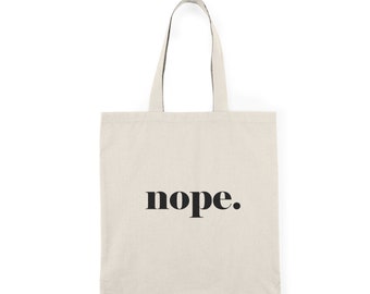 Könnte beinhalten: Eine beige Canvas-Tragetasche mit schwarzen Henkeln und dem Wort "nope." in fetten schwarzen Buchstaben.