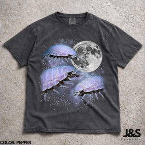 May include: Dark grey t-shirt with a graphic of purple woodlice, a full moon, and a starry night sky. The shirt has a vintage appearance and the text "J&S Essential" is visible.