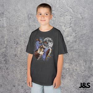 May include: Dark gray t-shirt featuring a graphic of three birds, a full moon, and a starry sky. The birds are depicted in shades of brown and white. The shirt is a short-sleeved crew neck.