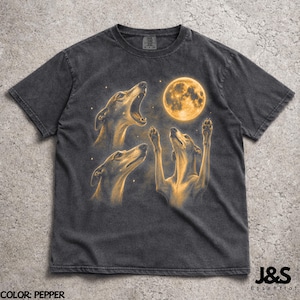 May include: Pepper-coloured t-shirt with a graphic of three greyhounds howling at a full moon. The design includes a detailed illustration of the dogs and the moon, with the text "J&S Essential" at the bottom.