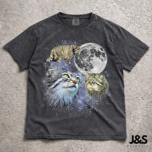 Peut inclure: T-shirt gris foncé avec un motif de trois chats, une pleine lune et un fond étoilé. Les chats sont dans des tons de gris, de marron et de vert. Le texte "J&S Essential" est en bas à droite.