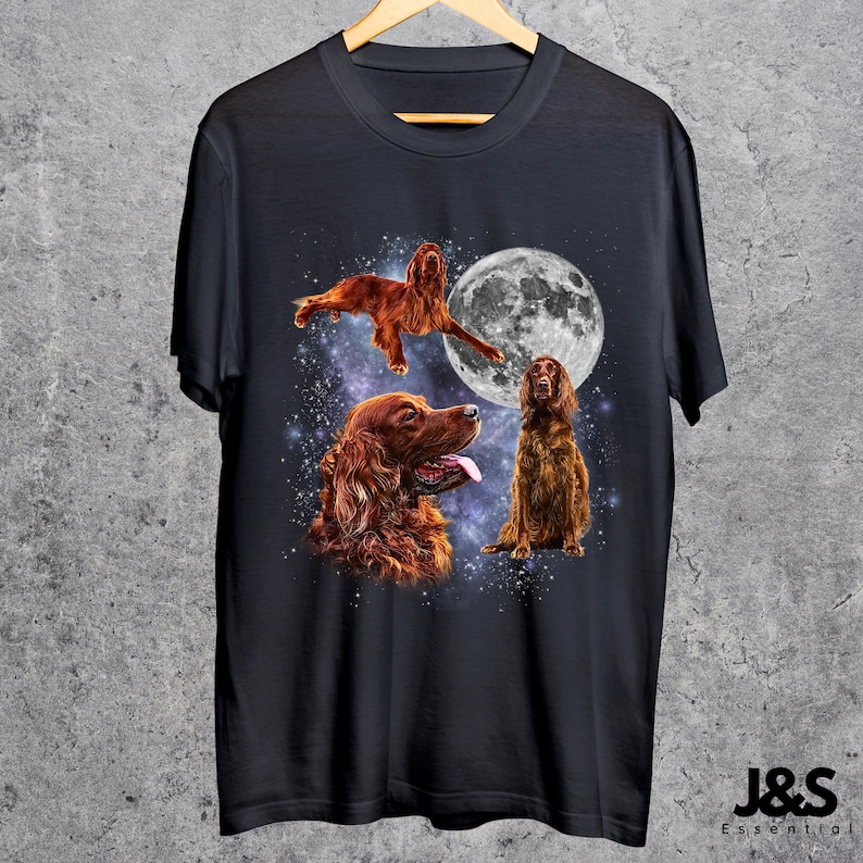 K&ouml;nnte beinhalten: Schwarzes T-Shirt mit einem Design von drei Irish Setter Hunden vor einem Sternenhimmel und einem Vollmond. Die Hunde sind in verschiedenen Posen dargestellt, darunter einer in der Luft, einer sitzend und einer mit herausgestreckter Zunge.
