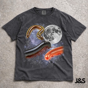 Peut inclure: T-shirt gris foncé avec un motif graphique de trois mille-pattes, une pleine lune et un fond étoilé. Le t-shirt a un aspect vintage et vieilli. Le texte "J&S Essential" est en bas à droite.