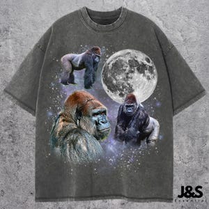 May include: Charcoal grey t-shirt with a graphic of three gorillas, a full moon, and a starry sky. The shirt has a worn appearance and the text "J&S Essential" is printed on the bottom right.
