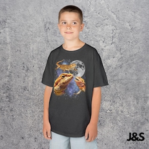May include: Dark gray t-shirt featuring a graphic of three bearded dragons with a full moon and a starry background. The lizards are in shades of orange and brown. The shirt has the text "J&S Essential" at the bottom.