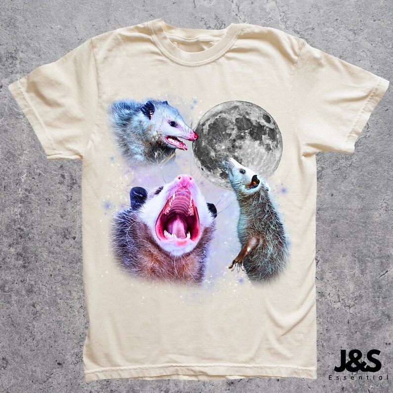 Pode incluir: Camiseta creme com um gr&aacute;fico de tr&ecirc;s gamb&aacute;s e uma lua cheia. Um gamb&aacute; boceja, outro olha para cima e o terceiro olha para o lado. A camisa tem o texto "J&S Essential" na parte inferior.