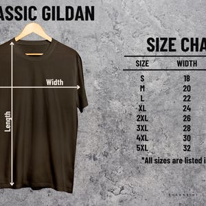 K&ouml;nnte beinhalten: Ein braunes T-Shirt h&auml;ngt an einem Holzb&uuml;gel, mit einer Gr&ouml;&szlig;entabelle rechts. Die Tabelle listet die Gr&ouml;&szlig;en S bis 5XL mit den entsprechenden Breiten- und L&auml;ngenma&szlig;en in Zoll auf. Der Text "CLASSIC GILDAN" steht oben.