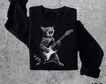 May include: Black sweatshirt with a graphic of a cat playing an electric guitar. The cat is singing and has a serious expression on its face.