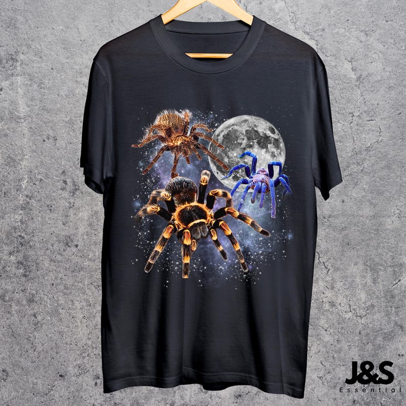 May include: Black t-shirt featuring a graphic of three spiders in front of a full moon and starry background. The spiders are brown, orange, and blue. The shirt has the text "J&S Essential" at the bottom.