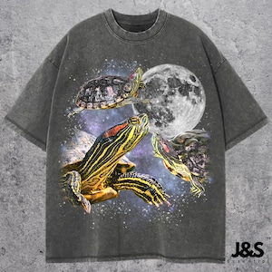 Op de afbeelding: Donkergrijs t-shirt met een afbeelding van drie schildpadden, een volle maan en een sterrenhemel. De schildpadden hebben gele, rode en zwarte markeringen. Het shirt heeft een relaxte pasvorm en korte mouwen.