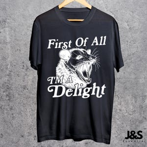 May include: Black t-shirt with a white graphic of an animal with the text "First Of All I'M A Delight".