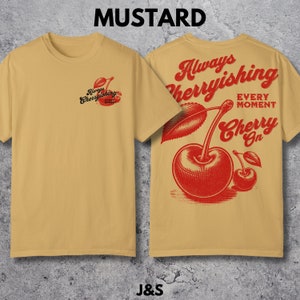 May include: Mustard yellow t-shirt with a red cherry graphic and the text "Always Cherryishing Every Moment Cherry On".