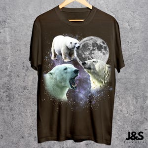 May include: Brown t-shirt featuring a graphic design of three polar bears with a full moon and a starry background. The polar bears are in different poses, with one yawning. The text "J&S Essential" is at the bottom right.