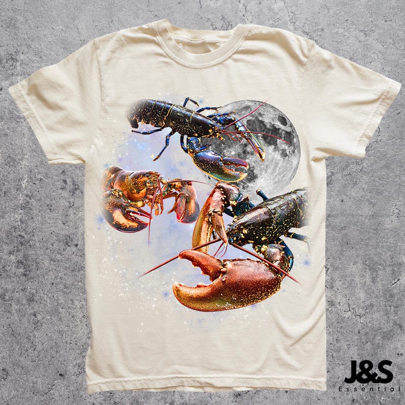 以下が含まれることがあります： クリーム色のTシャツ。赤、黒、青など様々な色のロブスターが、満月と星空を背景に描かれたグラフィック。クルーネックで半袖です。