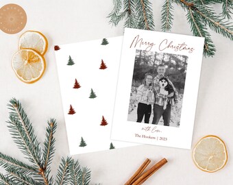 Può includere: Un biglietto di Natale con una foto in bianco e nero di una coppia e il loro cane. La carta ha un motivo di alberi di Natale rosso e bianco sul retro. Il testo sul fronte della carta recita "Buon Natale con amore, I Hookers | 2023".