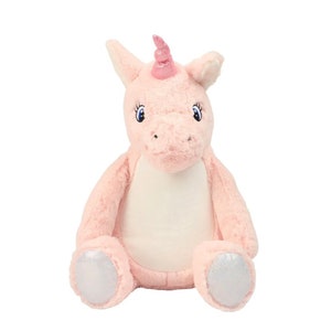May include: A soft pink unicorn toy with a light pink body, a white belly, and silver hooves. The unicorn has a pink horn and blue eyes with eyelashes. The toy is in a sitting position.