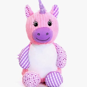 May include: A soft unicorn toy in pink and purple hues. The unicorn features a textured pink body, a purple snout, and a horn. The ears and limbs have patterned fabric with hearts and stripes. The toy is designed with a smiling face.