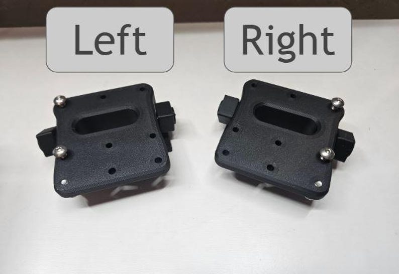 May include: Two black, rectangular mounting brackets with rounded corners, each featuring an oblong cutout and several small holes. Silver screws secure the components. The word "Left" is above one bracket, and "Right" is above the other.